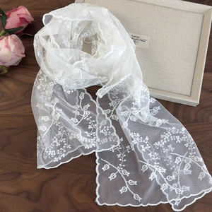 Écharpe élégante en dentelle blanche brodée sur table en bois avec des roses