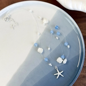 Detail of a three-strand ocean necklace with blue crystal beads and a silver starfish charm