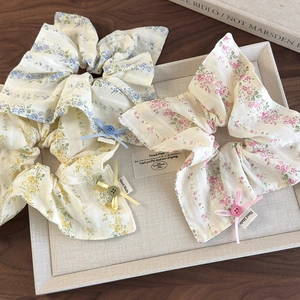 Close-up of floral hair scrunchies with ribbons and buttons on a beige tray