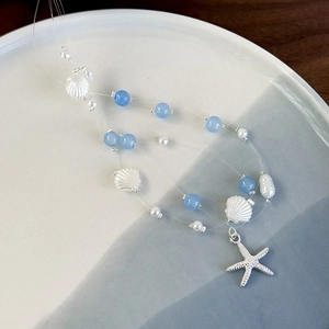 Macro detail of starfish charm and blue glass beads on three-layer ocean necklace