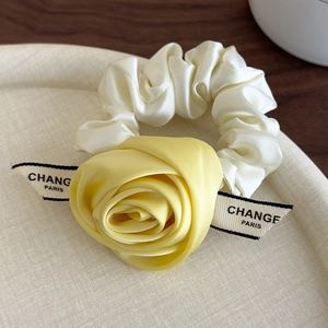 Detail of yellow satin rose hair scrunchie with cream ribbon and elegant pleats