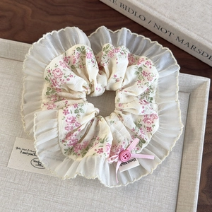 Detailed close-up of floral scrunchie with lace edges and a pink ribbon bow detail
