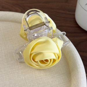 Detailed view of yellow fabric roses on a transparent acrylic hair clip clip with spring