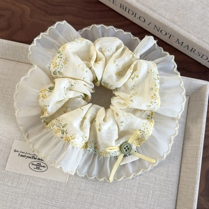 Detailed shot of floral scrunchie with yellow bow and green button on vintage tray