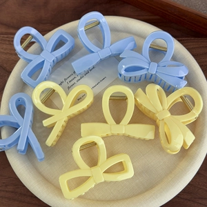 Pinces à cheveux en forme de nœud bleu pastel et jaune disposées sur un plateau chic