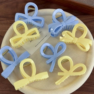 Pinces à cheveux nœud bleu et jaune crème présentées sur un plateau rond crème