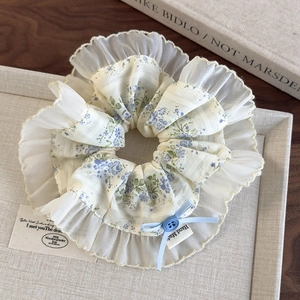 Detailed macro view of floral print hair scrunchie with lace trim and blue ribbon bow knot