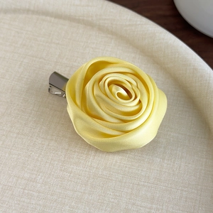 Close-up of elegant yellow satin rose hair clip with rich floral petal layers