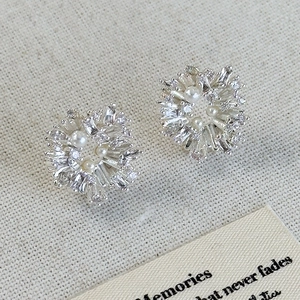 Elegant silver flower pearl stud earrings with sparkling cubic zirconia on linen background