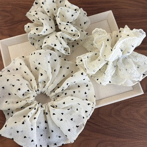 Three-piece set of cream scrunchies featuring heart patterns and delicate lace ruffles