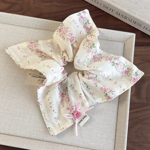 Detailed shot of cream floral scrunchie with pink ribbon bow and handmade label