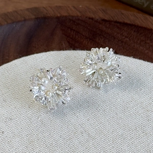 Macro shot of silver fireworks flower earrings with sparkling zircons and white pearls