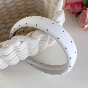 Détail d'un serre-tête à pois blancs sur un panier tressé avec rose décorative