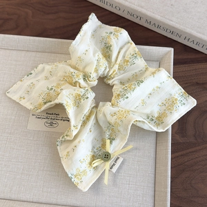 Detail of floral scrunchie with yellow bow, green button, and Hand Made label