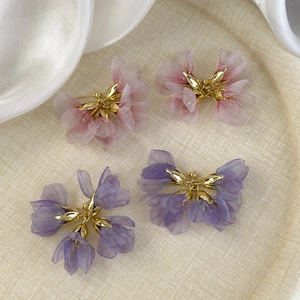 Close-up of sweet purple and pink mesh petal earrings with elegant golden metal flower centers