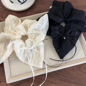 Detailed view of lace scrunchies with bow ribbon and rhinestones on a wooden tray