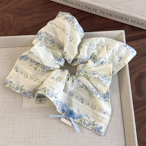 Detailed macro view of a floral scrunchie with blue bow and button on display tray