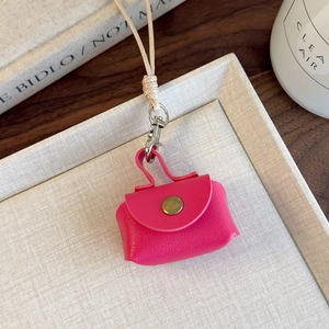 Gros plan du mini porte-monnaie en cuir rose avec cordon sur un plateau beige