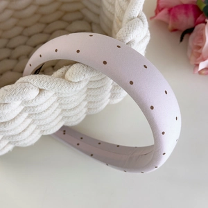 Gros plan d'un serre-tête large en tissu rose à pois marrons avec rembourrage doux