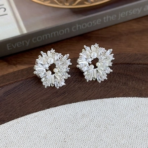 Detail of flower-shaped stud earrings with pearls and zircons on a rustic backdrop