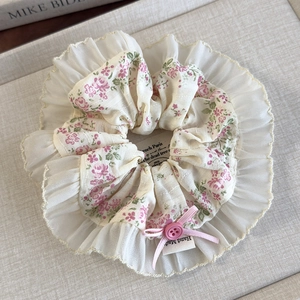 Detailed macro of floral scrunchie with lace edge, pink ribbon bow and button detail