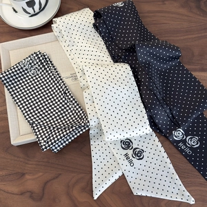 Macro shot of camellia polka dot silk neck scarf with Hello print on a wooden desk
