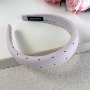 Détail d'un serre-tête rose à pois avec étiquette faite main et texture en tissu doux