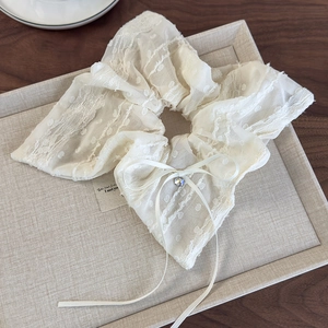Detail view of white lace scrunchie featuring a delicate bow and sparkling rhinestone centerpiece