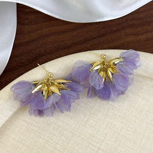 Close-up of purple mesh flower earrings with golden metal details for beach vacations