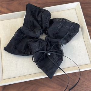 Detail of black lace bow scrunchie with rhinestones and long silk ribbons on a display tray