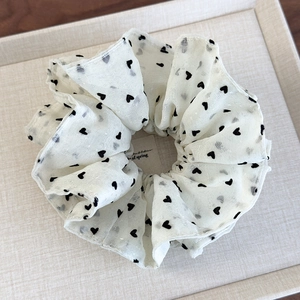 Detail of cream tulle scrunchie with black heart pattern and subtle silver glitter silk