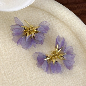 Detailed macro view of romantic purple mesh fabric flower earrings with gold metal centers