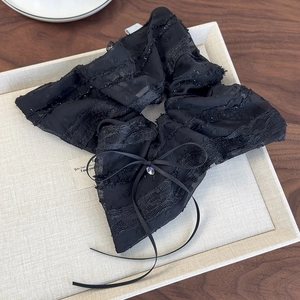 Detail of elegant black lace bow hair tie featuring polka dots and a sparkling rhinestone