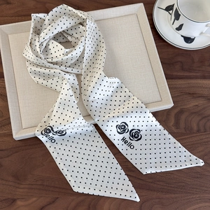 Detail shot of a polka dot silk twilly scarf with black rose and Hello lettering