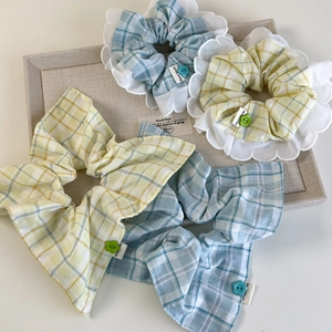 Detail of plaid scrunchie with lace trim and flower button on a jewelry tray