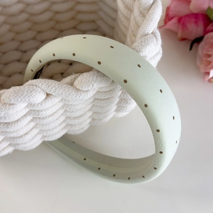 Détail d'un serre-tête vert clair à pois avec tissu doux et design rembourré