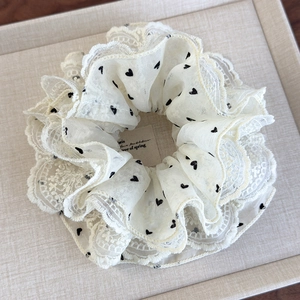 Detail of white lace scrunchie with black heart polka dots and pleated mesh design