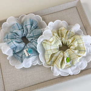 Close-up of mint and yellow plaid scrunchies with lace edges and floral buttons