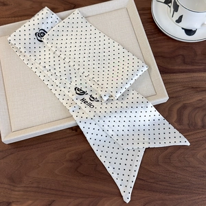 Polka dot silk scarf with black rose patterns and swallowtail design on a chic tray