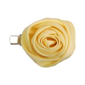Detail of handmade light yellow satin rose hair clip with elegant fabric texture