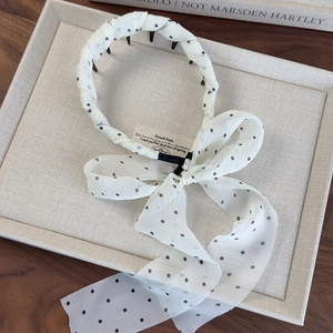 Close-up of white polka dot chiffon headband with bow and nonslip inner teeth detail