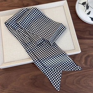Detail of black and white checkerboard silk scarf on a tray with smooth satin texture