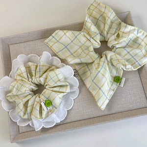 Detail of plaid scrunchies with white lace edges and decorative green flower buttons