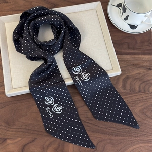 Detail of silk scarf with black white polka dots and white rose pattern on wooden table