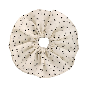 Detailed close-up of white mesh scrunchie featuring black heart patterns and soft pleats