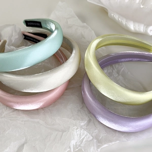 Detail of macaron-colored pearl satin headbands stacked on elegant white art paper