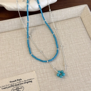 Collier ethnique avec perles bleues et pendentif fleur dans un design argenté superposé