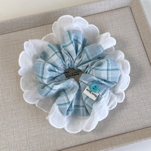 Detailed view of sky blue checkered scrunchie with lace edges and a flower button