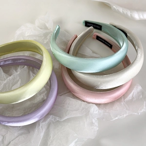 Detail of five colorful satin padded headbands with handmade labels on white paper