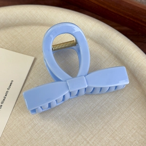 Gros plan d'une pince à cheveux en acrylique bleu clair avec ressort en métal doré